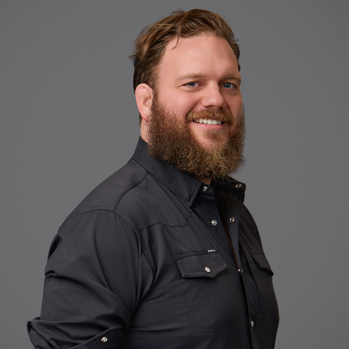 Professional headshot of Austin Spires smiling against a gray background